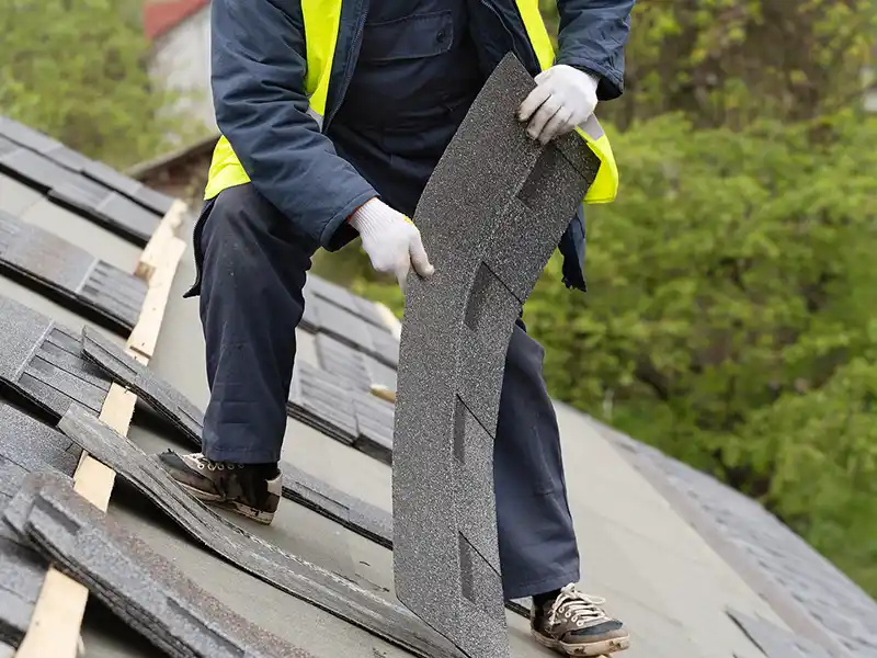 Roofer placing asphalt shingles